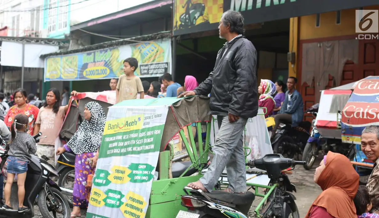 Seorang warga berdiri di atas motor menunggu kirab atau arak-arakan acara resepsi Kahiyang Ayu Siregar-Bobby Nasution di Kota Medan, Sumatera Utara Minggu (26/11). (Liputan6.com/Johan Tallo)