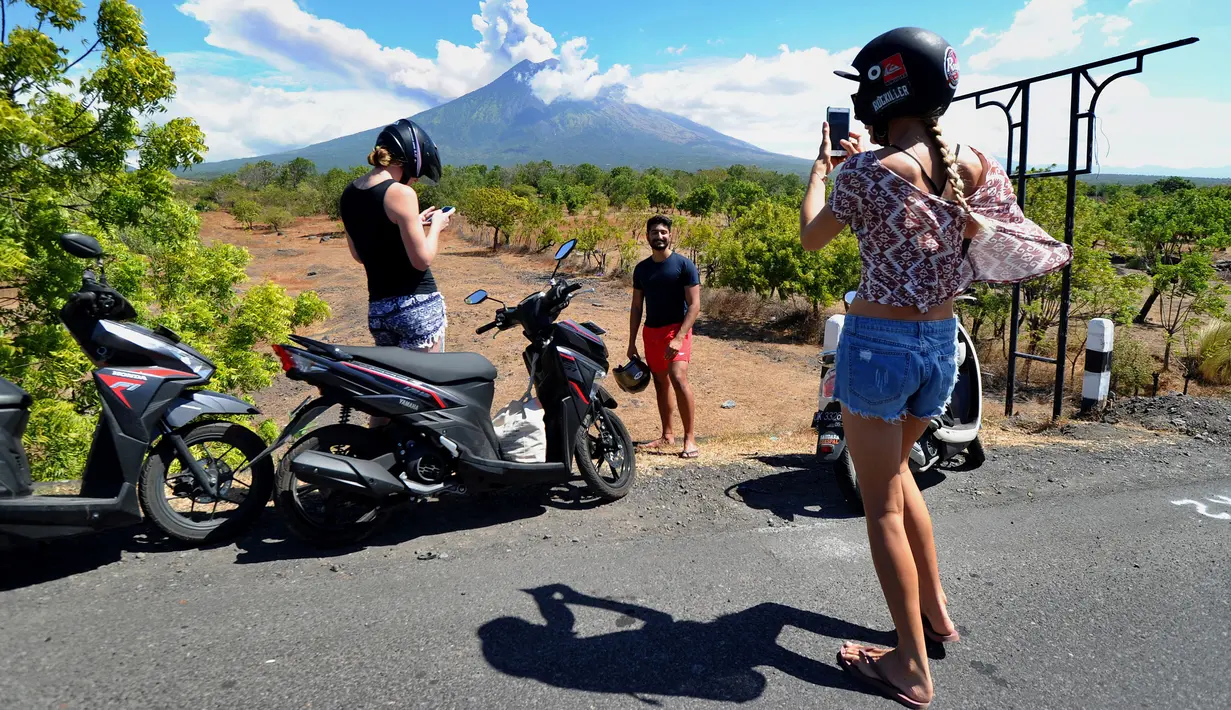Sejumlah turis mengabadikan pemandangan erupsi Gunung Agung di Kabupaten Karangasem, Bali, Jumat (6/7). Erupsi Gunung Agung mengundang banyak perhatian warga dan wisatawan. (AFP FOTO / Sonny Tumbelaka)