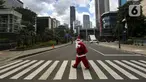 Pria berkostum Sinterklas menyeberang jalan saat membagikan kopi gratis kepada warga di kawasan Jalan Jenderal Sudirman, Jakarta, Sabtu (19/12/2020). Pembagian kopi tersebut bertujuan untuk menyambut perayaan Natal 2020. (Liputan6.com/Johan Tallo)