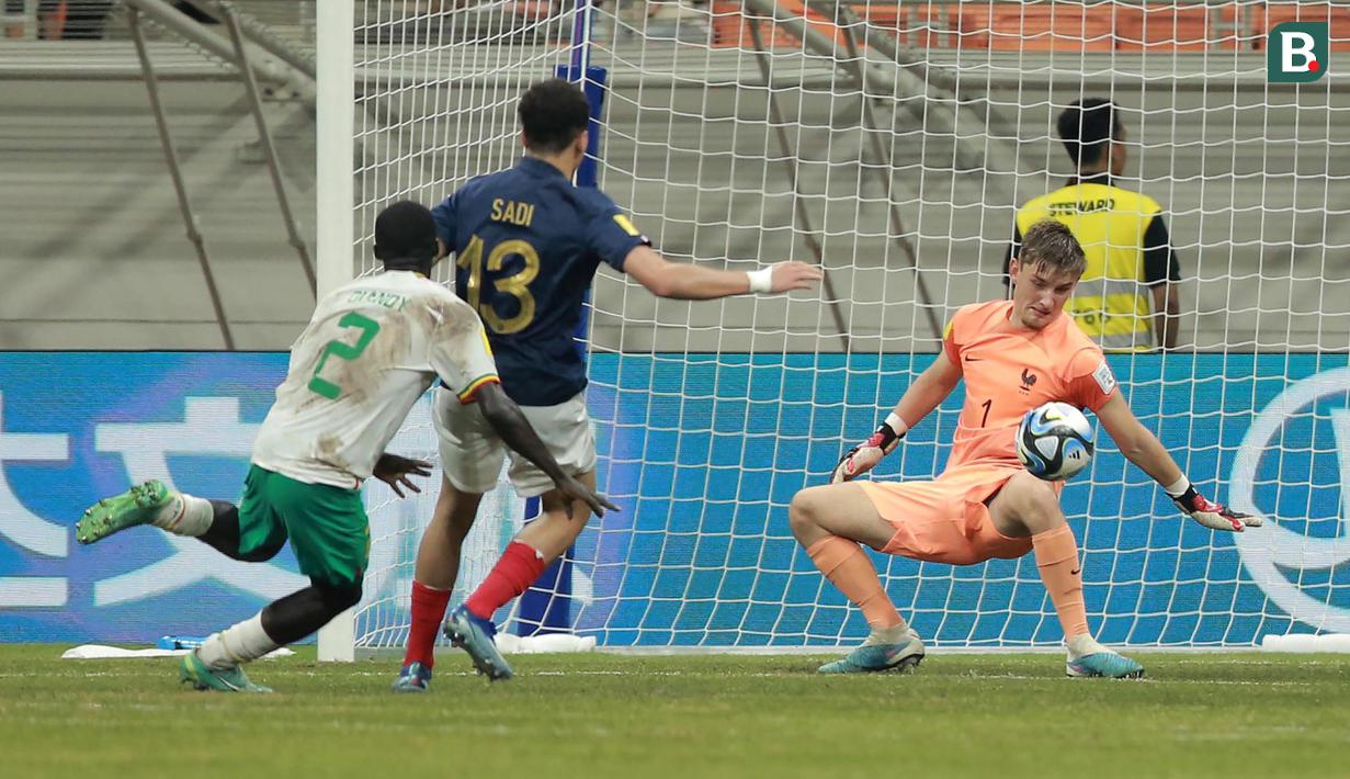 Kiper Timnas Prancis U-17, Paul Argney membuat penyelamatan hasil tendangan pemain Timnas Senegal U-17, Clayton Diandy (kiri) pada laga babak 16 besar Piala Dunia U-17 di Jakarta International Stadium, Jakarta Utara, Rabu (22/22/2023) malam WIB. (Bola.com/M Iqbal Ichsan)