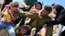 Foto yang diambil pada 28 Agustus 2015 menunjukkan Ahed Tamimi (kiri) menggigit tangan tentara Israel saat berkelahi bersama keluarganya karena terjadi bentrokan di Desa Nabi Saleh. (AFP Photo/Abbas Momani)