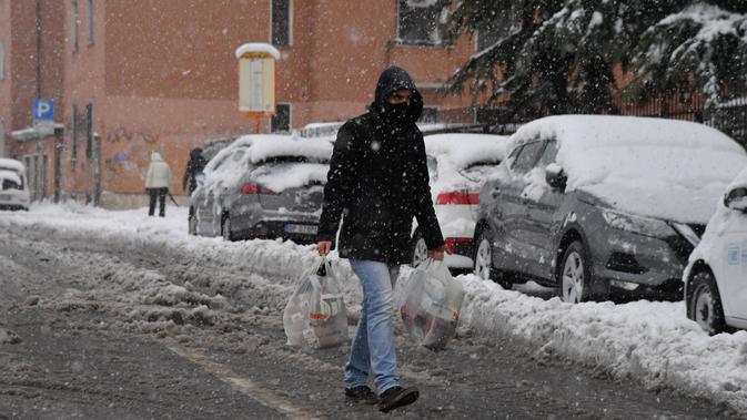 Seorang pria berjalan di tengah salju di Milan, Italia utara (28/12/2020). Hujan salju mengguyur Milan pada Senin (28/12). (Xinhua/Daniele Mascolo)