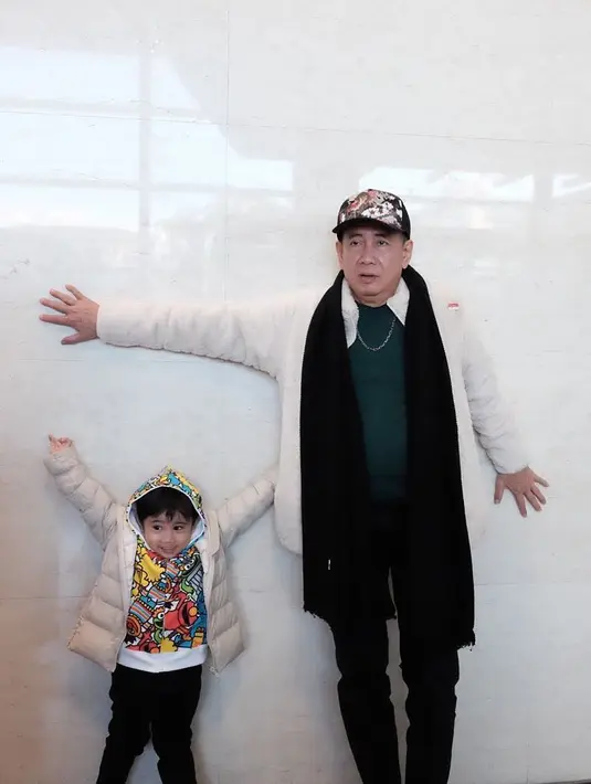 Kalau yang satu ini, mendiang Sys kompak bareng cucu lelakinya yang bernama Sréstha. Mereka sama-sama mengenakan baju hangat dan berpose menempelkan tubuh di dinding. (Instagram/sys_ns)