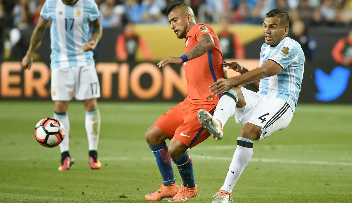 Gelandang Chile, Arturo Vidal (tengah) berusaha mengontrol bola dari kawalan bek Argentina, Gabriel Mercado pada Copa America Centenario 2016 di Levi's Stadium, California, AS (7/6). Argentina menang atas Chile dengan skor 2-1. (AFP/Mark Ralston)