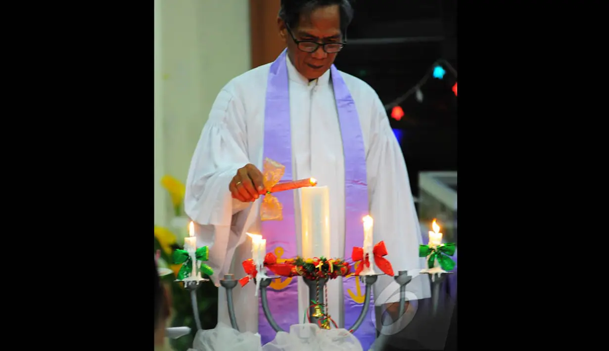 Pendeta saat menyalakan lilin pada Misa Natal di Gereja "Ayam" GPIB Pniel Jakarta, Rabu (24/12/2014). (Liputan6.com/Faisal R Syam)