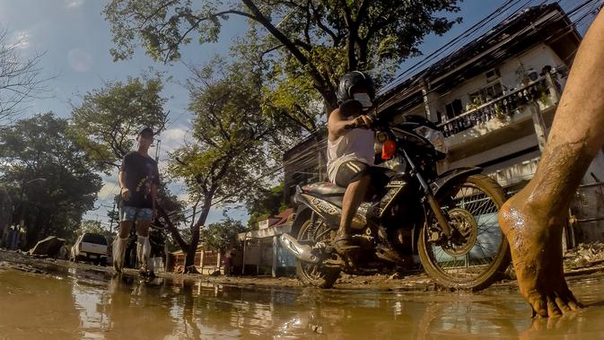 Warga berjalan di sebuah jalan yang tertutup lumpur akibat banjir yang dipicu Topan Vamco di Manila, Filipina (13/11/2020). Pemerintah Filipina pada Jumat (13/11) mengatakan Topan Vamco, yang memicu banjir besar dan tanah longsor menelan sedikitnya 14 korban jiwa. (Xinhua/Rouelle Umali)