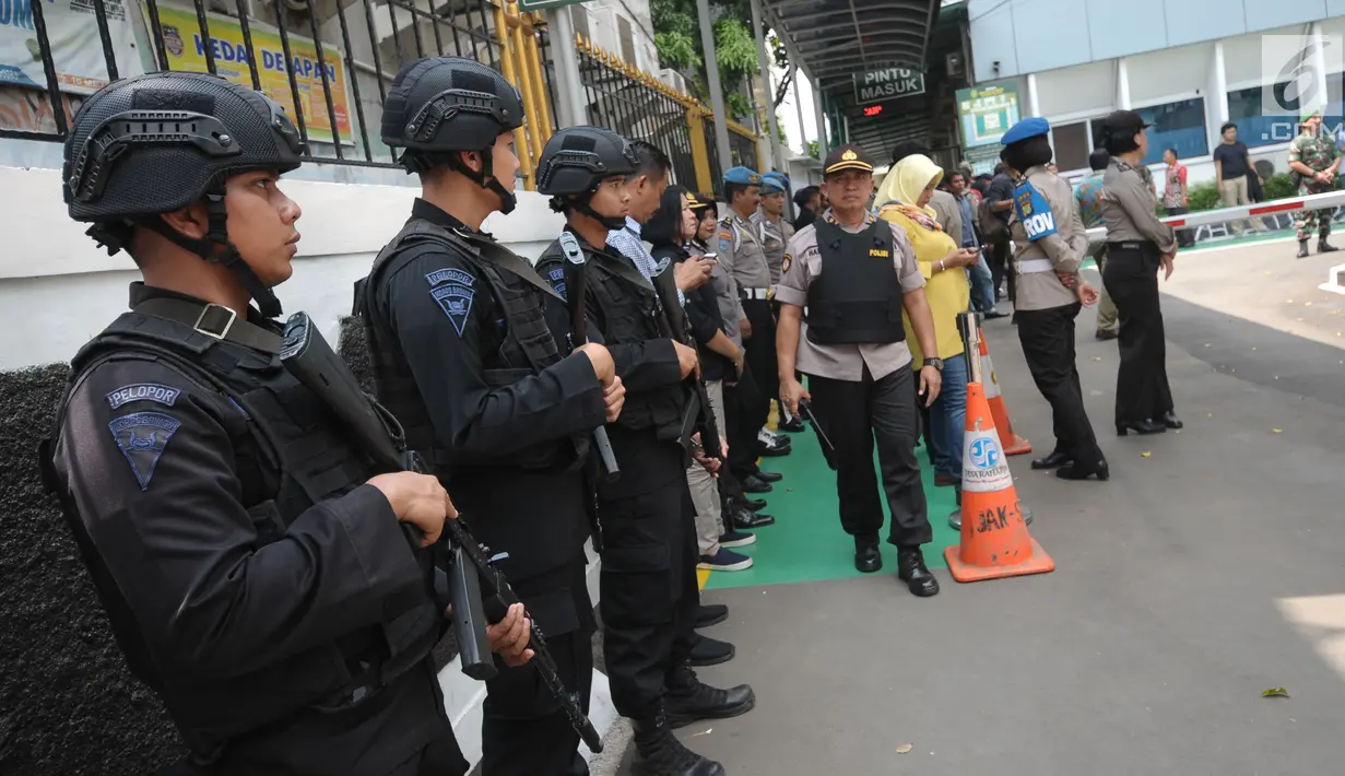 Personel Brimob bersenjata lengkap berjaga di depan gerbang masuk PN Jakarta Selatan saat sidang pembacaan tuntutan terhadap terdakwa sejumlah kasus tindak pidana terorisme, Aman Abdurrahman, Jumat (18/5). (Liputan6.com/Helmi Fithriansyah)