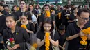 Warga Thailand mengenakan pakain hitam dan membawa bunga saat memberi penghormatan untuk mendiang Raja Thailand Bhumibol Adulyadej di luar Grand Palace, Bangkok, Thailand (13/10). (AP Photo/Gemunu Amarasinghe)