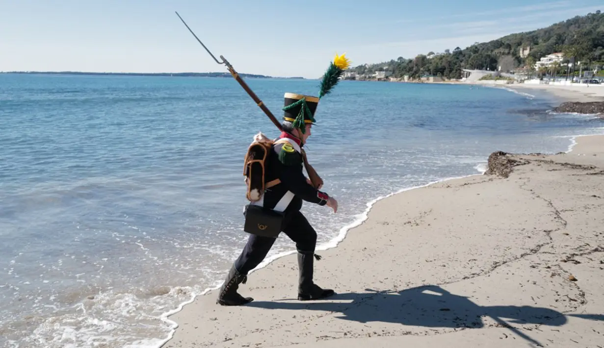Seorang pria yang mengenakan kostum seperti tentara era Napoleon Bonaparte berjalan di pantai dalam rangka peringatan 200 tahun kematian Napoleon Bonaparte di Saint-Helene, Golfe-Juan, Prancis, 16 Maret 2021. Napoleon memiliki pengaruh besar terhadap persoalan-persoalan Eropa. (Valery HACHE/AFP)