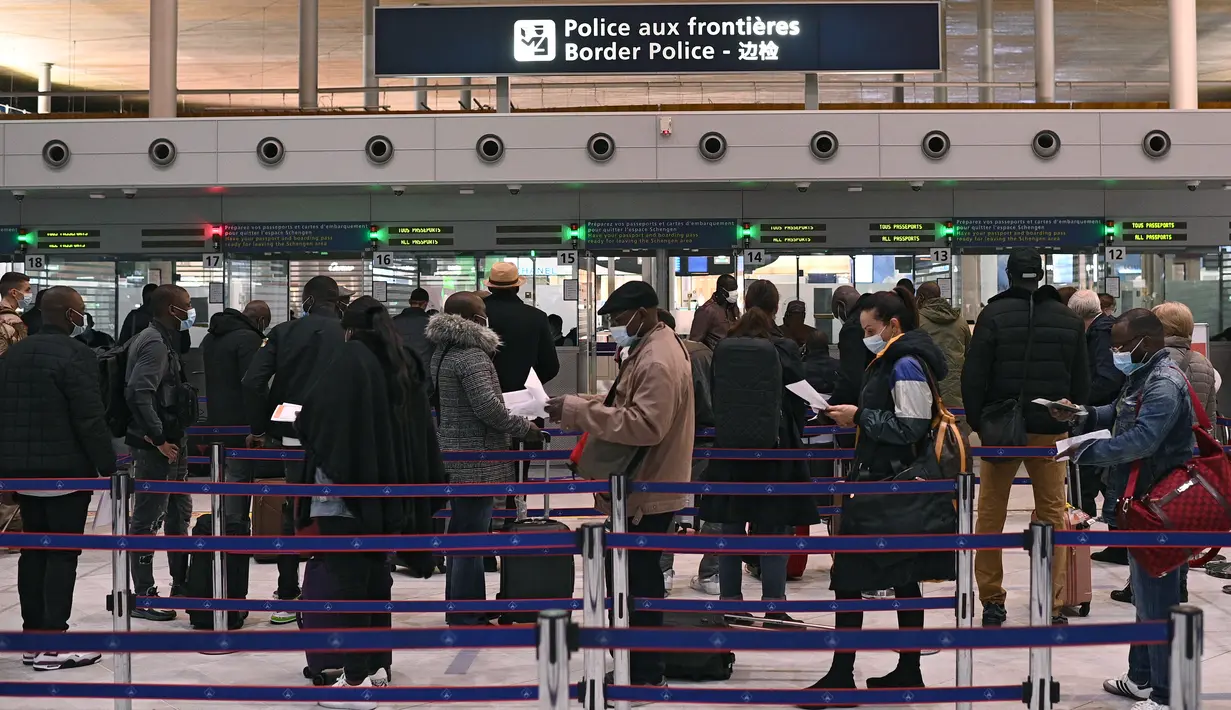Wisatawan mempersiapkan dokumen mereka saat mengantre di meja imigrasi bandara internasional Roissy Charles-de-Gaulle, Paris, Senin (1/2/2021). Selain "alasan luar biasa", semua perjalanan penting dari luar Uni Eropa telah dilarang di Prancis. (AP Photo/Francois Mori)