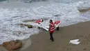 Kelompok Bulan Sabit Merah Libya memasukkan jenazah yang diduga imigran yang tewas tenggelam, ke kantong mayat di pantai Khoms, sebelah timur Tripoli, Minggu (25/10). Sedikitnya 40 jasad telah ditemukan di pantai Libya. (REUTERS/Ismail Zitouny)