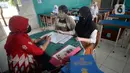 Guru Wali Kelas berdiskusi dengan wali murid saat pembagian raport di SMP Negeri 18 Tangerang Selatan, Banten, Kamis (17/12/2020). Pembagian raport diketahui sedang dilaksanakan sejumlah sekolah.  (merdeka.com/Dwi Narwoko)