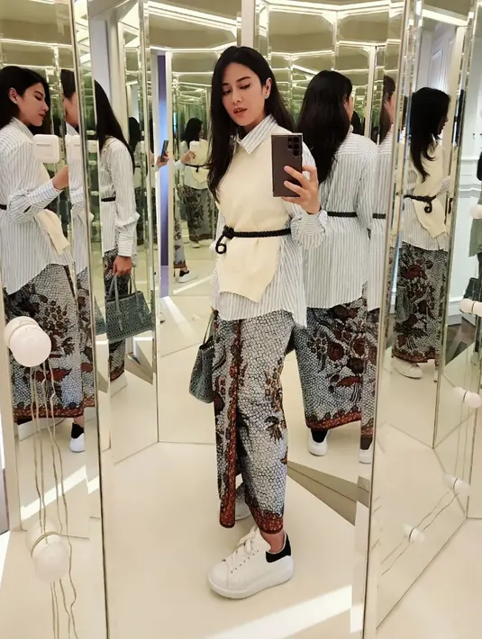 Dian Sastro aplikasikan preppy look-nya saat kenakan wastra. Ia kenakan kemeja bergaris dengan vest putih dan rok lilit batik [@therealdisastr]