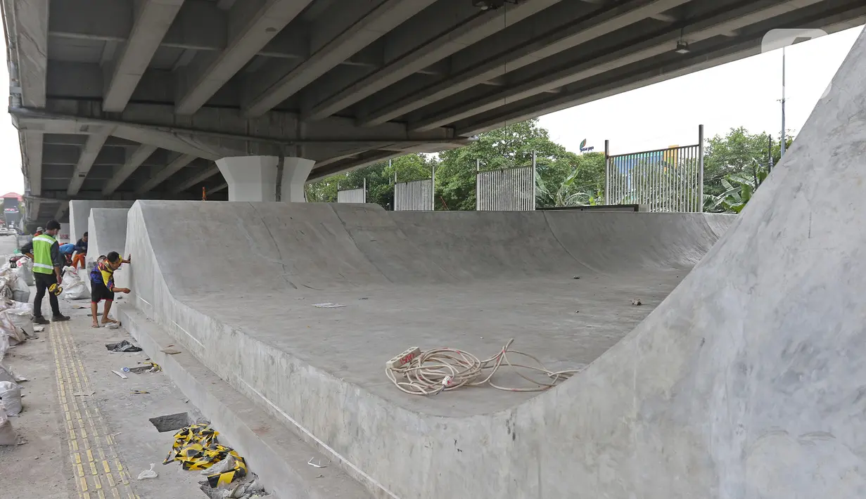 Pekerja menyelesaikan pembangunan Skate Park kolong Flyover Pasar Rebo, Jakarta, Selasa (10/12/2019). Adapun anggaran untuk pembuatan skatepark tersebut sebesar Rp14,3 miliar. (Liputan6.com/Herman Zakharia)