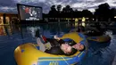 Penonton film tersenyum menunggu pemutaran film Steven Spielberg "Jaws" dengan ban karet di kolam renang di Brockwell Lido, London, Inggris, Kamis (17/9/2015). (REUTERS/Luke MacGregor)