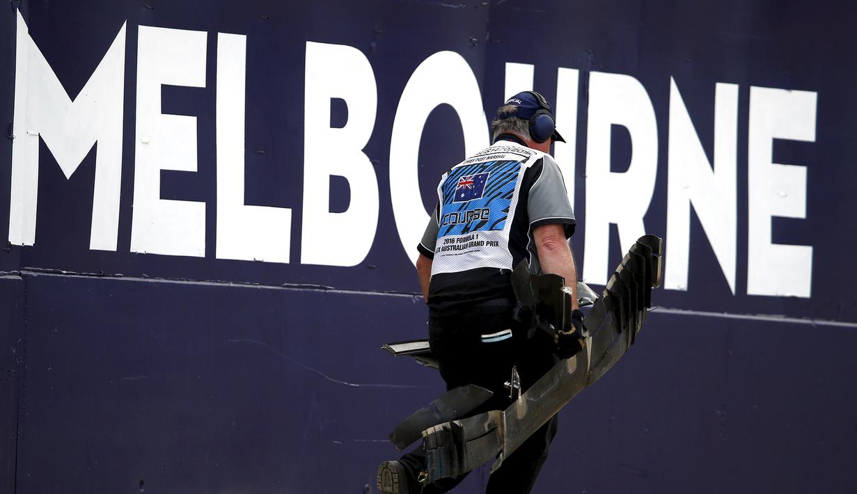 Marshal membawa puing mobil balap yang hancur akibat kecelakaan antara pembalap McLaren Fernando Alonso dan pembalap Haas, Esteban Gutierrez pada pertarungan di lap 17 F1 Grand Prix Australia di Melbourne,  Minggu (20/3). (REUTERS/Joe Castro)