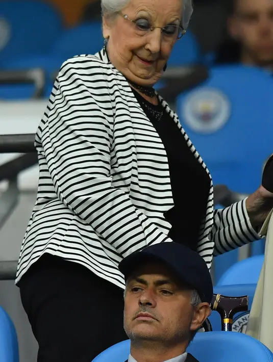 Pelatih Manchester United, Jose Mourinho memakai topi saat menyaksikan pertandingan Manchester City melawan Everton pada Liga Inggris di Stadion Etihad, (22/8). (AFP Photo/Anthony Devlin)
