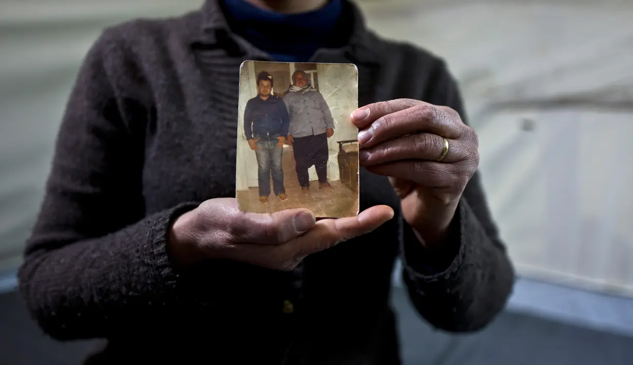 Habeeba Waqas (40) dari Aleppo menunjukkan foto suaminya, Mohammed dan ayahnya di tendanya di kamp pengungsian Frakapor, Yunani 18 Januari 2017. Ia mengungkapkan, ini adalah satu-satunya memori yang saya bawa dari Suriah. (AP Photo / Muhammed Muheisen)