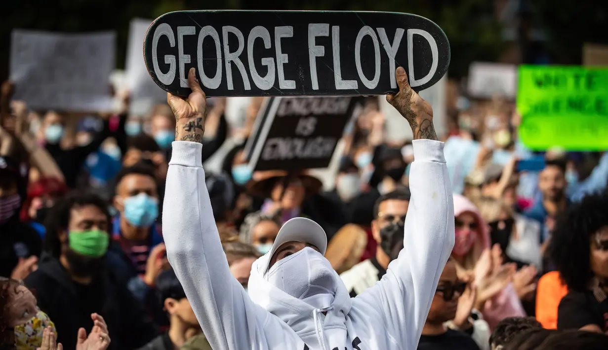 Seorang pria memegang skateboard bertuliskan nama George Floyd ketika berunjuk rasa dalam mendukung Floyd dan Regis Korchinski-Paquet dan protes terhadap rasisme, ketidakadilan dan kebrutalan polisi, di Vancouver (31/5/2020). (Darryl Dyck/The Canadian Press via AP)
