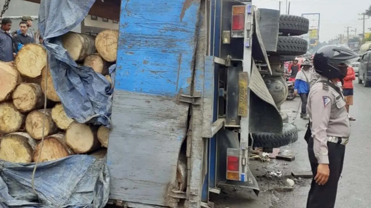 Truk muatan kayu terguling