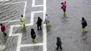 Warga berjalan di Alun-Alun Santo Markus yang banjir akibat terjangan gelombang pasang di Venesia, Italia, Selasa (12/11/2019). Venesia dilanda banjir akibat gelombang pasang setinggi 127 cm. (AP Photo/Luca Bruno)