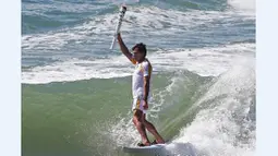 Atlet surfing Brasil, Carlos Burle, membawa obor api Olimpiade Rio 2016 saat melewati kota Porto de Galinhas, Ipojuca, Brasil, (1/6/2016). (AFP/RIO2016/Marcos de Paula)