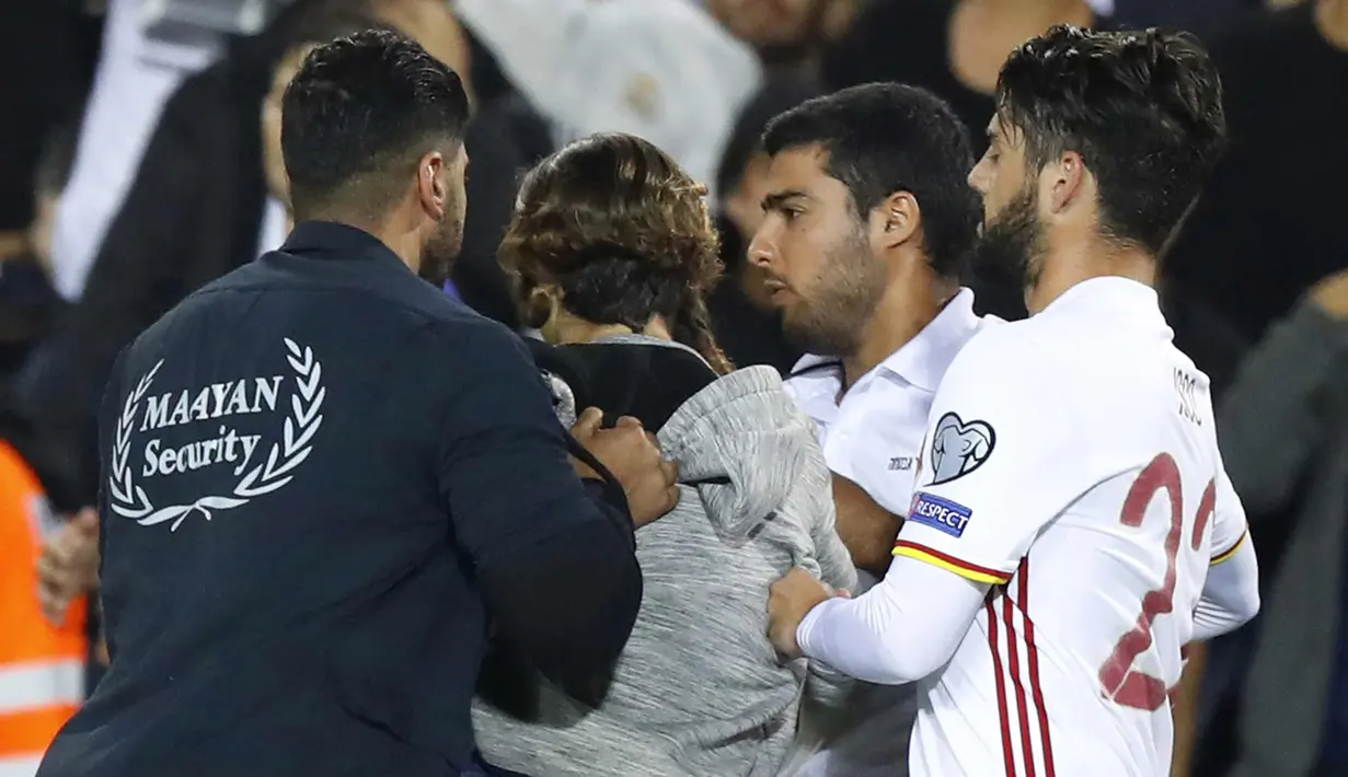Petugas membawa pria yang mendekati gelandang Isco saat pertandingan kualifikasi Piala Dunia 2018 antara Israel melawan Spanyol di Stadion Teddy di Yerusalem (9/10). Enam suporter Israel ditangkap polisi usai laga tersebut. (AFP Photo/Jack Dan Jack Guez)