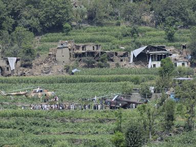 Warga setempat berkumpul di sekitar helikopter militer yang mendarat untuk memberikan bantuan dan mengevakuasi korban luka akibat gempa bumi yang menghancurkan desa-desa di Afghanistan timur, Mazar Dara, Provinsi Kunar, Afghanistan, Senin 1 September 2025. (AP Photo/Wahidullah Kakar)