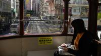 Seorang wanita mengenakan masker saat naik trem di Hong Kong, 8 Maret 2022. COVID-19 varian Omicron yang menyebar cepat membanjiri Hong Kong membuat kamar jenazah penuh, memaksa pihak berwenang untuk menyimpan jenazah dalam kontainer pengiriman berpendingin. (AP Photo/Kin Cheung)