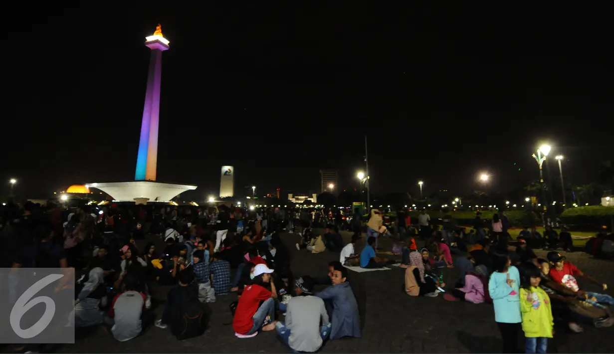 Pengunjung duduk duduk di halaman Monumen Nasional, Jakarta, Sabtu (31/12). Meski panggung hiburan malam pergantian tahun dibatalkan namun pengunjung tetap memadati kawasan Monumen Nasional . (Liputan6.com/Helmi Fithriansyah)