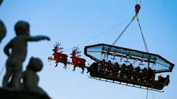 Para tamu menikmati makan malam di "Santa in the sky", yang diangkat dengan crane dan dihias menyerupai "Santa Sleigh" di Brussels, Belgia, 25 November 2016. Tempat ini didekorasi seperti kereta Santa Claus menjelang perayaan Natal. (REUTERS/Yves Herman)