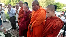 Sejumlah biksu bersama warga berdoa di depan sebuah stupa yang berisi ratusan tengkorak manusia dan tulang korban rezim Khmer Merah di Choeung Ek memorial, Kamboja (17/4). (AP Photo/Heng Sinith)