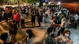 Pasangan mengenakan masker menari di sebuah taman di sebelah Sungai Yangtze, Wuhan, provinsi Hubei tengah China (12/5/2020).  Peningkatan kasus virus corona tersebut memicu kekhawatiran gelombang kedua infeksi. (AFP/Hector Retamal)