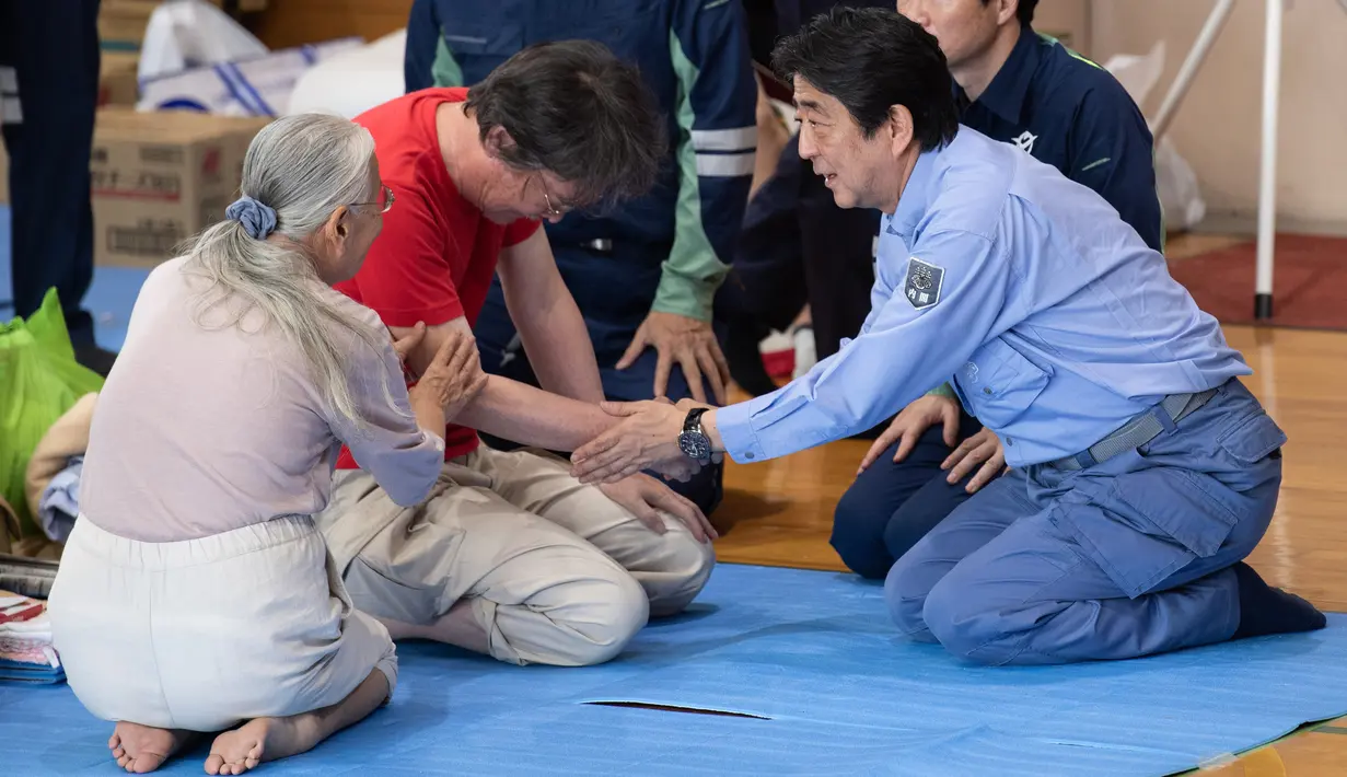 Perdana Menteri Jepang Shinzo Abe mengunjungi lokasi penampungan korban banjir di Mabi, Prefektur Okayama, Rabu (11/7). Abe mengunjungi daerah Okayama yang dilanda banjir dan melihat besarnya skala kerusakan secara langsung. (AFP/Martin BUREAU)
