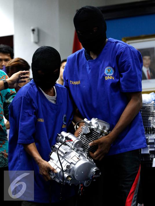 Tersangka  membawa barang bukti mesin sepeda motor berisi sabu di Jakarta, Jumat (28/8/2015). BNN berhasil membongkar penyelundupan sabu seberat 103,8 kilogram yang dimasukkan ke dalam mesin sepeda motor dan alat pijat. (Liputan6.com/Yoppy Renato)
