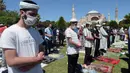 Umat Muslim berdoa saat menunaikan salat Jumat dengan latar belakang situs bersejarah Hagia Sophia di distrik bersejarah Sultanahmet di Istanbul, Jumat (24/7/2020). Hari ini, Hagia Sophia menyambut umat Islam melaksanakan salat Jumat pertama dalam 86 tahun.(AP Photo/Yasin Akgul)