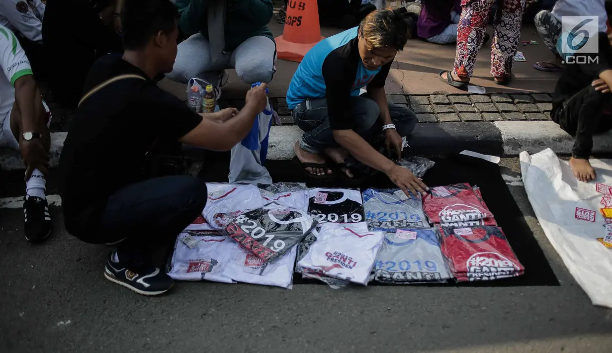 Pembeli memilih kaus #2019GantiPresiden yang dijajakan pedagang saat Car Free Day di Bundaran HI, Jakarta, Minggu (29/4). Memanasnya suasana politik nasional dimanfaatkan pedagang berjualan atribut #2019GantiPresiden. (Liputan6.com/Faizal Fanani)