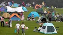 Sepasang suami istri melewati orang-orang yang berkemah di gunung yang indah di Yanqing, pinggiran Beijing, 30 Agustus 2020. China memiliki lebih dari 200 orang yang dirawat di RS karena COVID-19, dengan lebih dari 300 lainnya diisolasi usai dites positif terkena virus tanpa gejala. (AP/Andy Wong)
