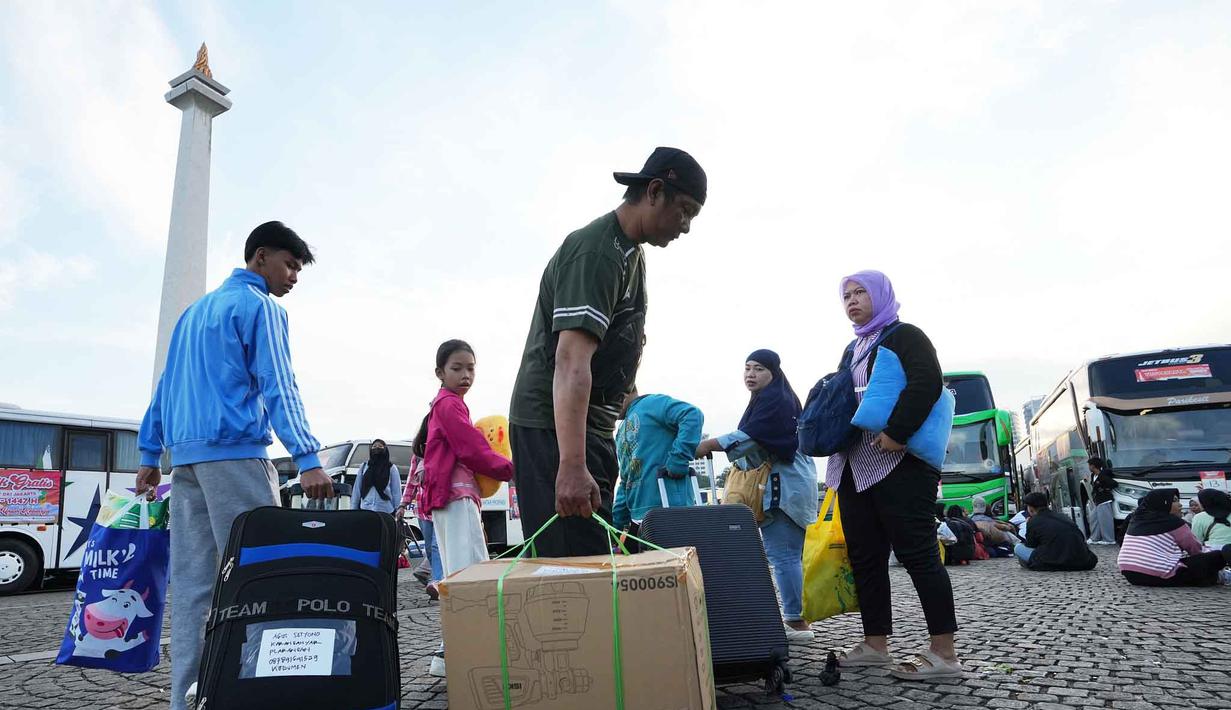 Angka ini meningkat dari target awal sekitar 30.774 orang karena tingginya antusiasme warga. Tampak dalam foto, orang-orang membawa barang-barang mereka saat tiba untuk perjalanan mudik gratis yang diselenggarakan oleh Pemerintah Provinsi Jakarta di Lapangan Monumen Nasional, Selasa 17 Maret 2026. (AP Photo/Achmad Ibrahim)