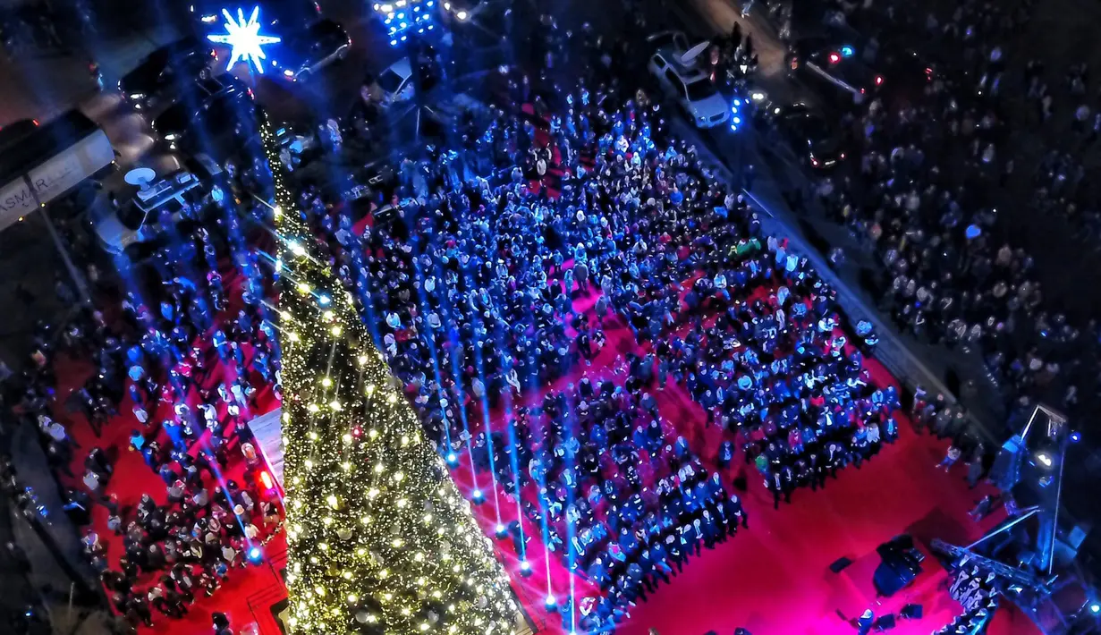 Warga mengikuti peresmian menyalakan lampu pohon natal di Beirut, Lebanon (10/12). Menyambut datangnya natal, warga Beirut merayakan peresmian pohon natal yang dipajang bersebelahan dengan Masjid Mohammad al-Amin. (AFP Photo/Stringer)