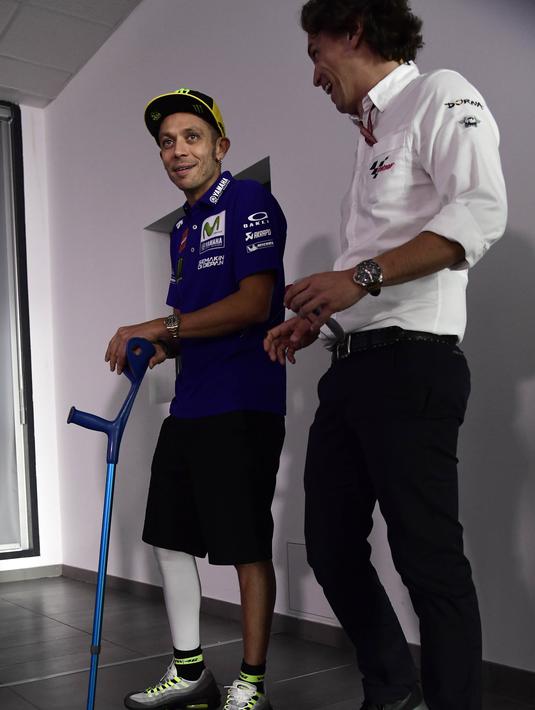 Pebalap Movistar Yamaha, Valentino Rossi, menggunakan tongkat menghadiri jumpa pers jelang GP Aragon di Alcaniz, Aragon, Kamis (21/9/2017). Rossi dinyatakan lolos tes medis untuk mengikuti balapan MotoGP Aragon. (AFP/Javier Soriano)