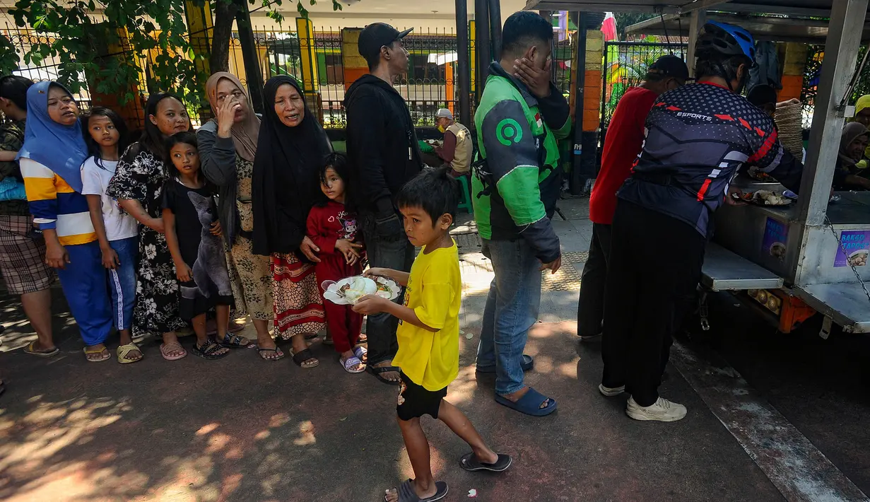 Warga antre mendapatkan sepiring nasi sayur dan lauk pauk saat pembagian makan siang gratis di wilayah Jati Padang, Pasar Minggu, Jakarta Selatan, Selasa (13/8/2024). (merdeka.com/Arie Basuki)