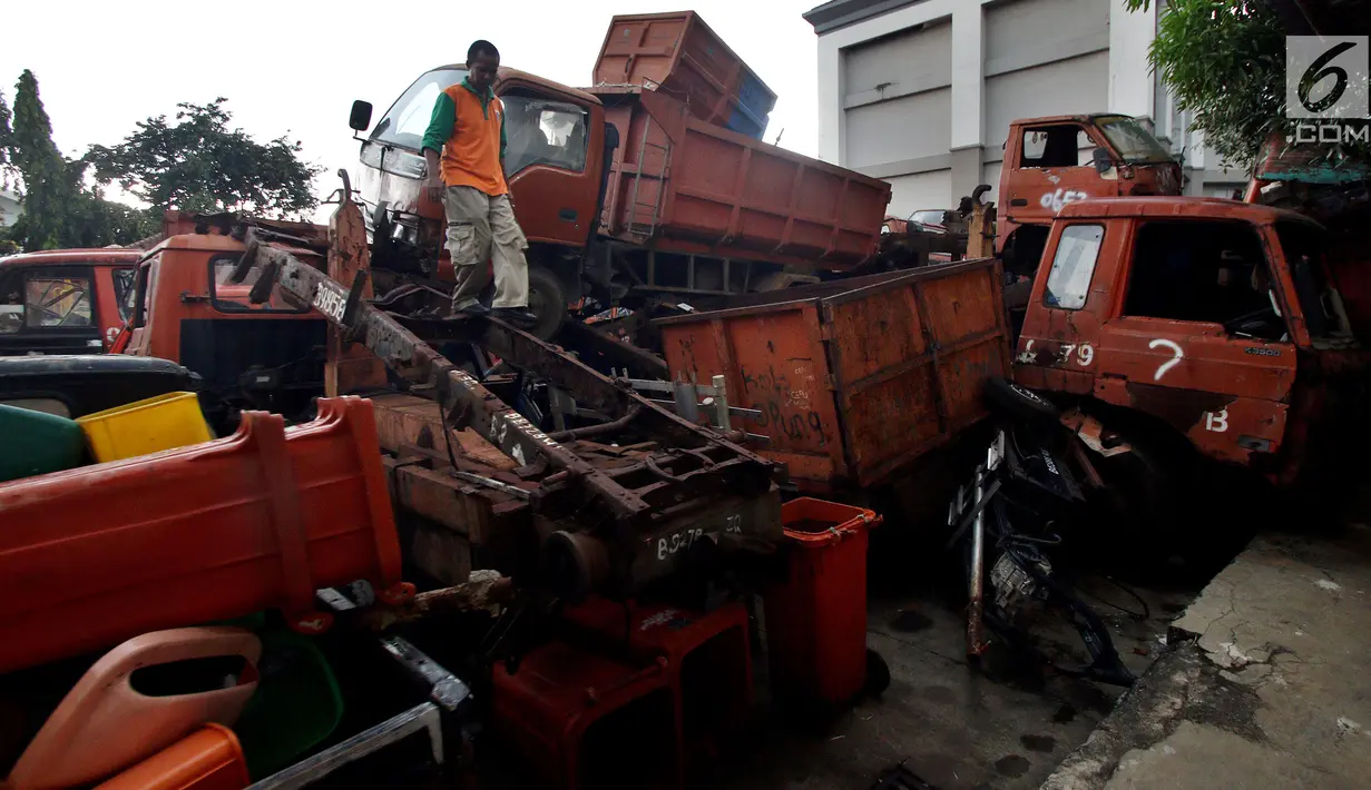 Petugas melakukan pengecekan bangkai armada truk sampah di Kantor Suku Dinas Lingkungan Hidup, Jakarta Barat, Selasa (27/3). Sebanyak 30 armada truk sampah diparkir dengan cara ditumpuk. (Liputan6.com/JohanTallo)