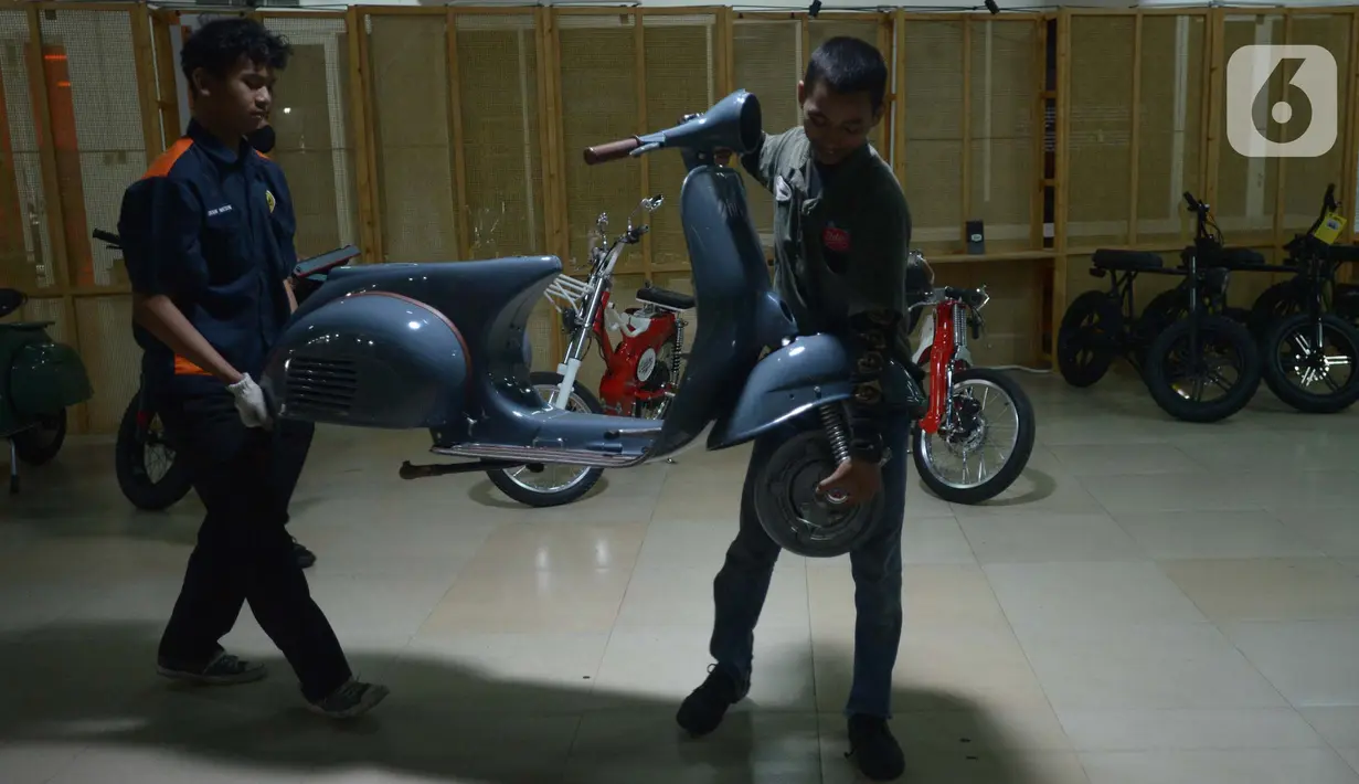 Mekanik membawa motor untuk dimodifikasi di Jakarta, Selasa (29/3/2022). Modifikasi motor tersebut merupakan konversi  bahan bakar minyak ke motor listrik. (merdeka.com/Imam Buhori)