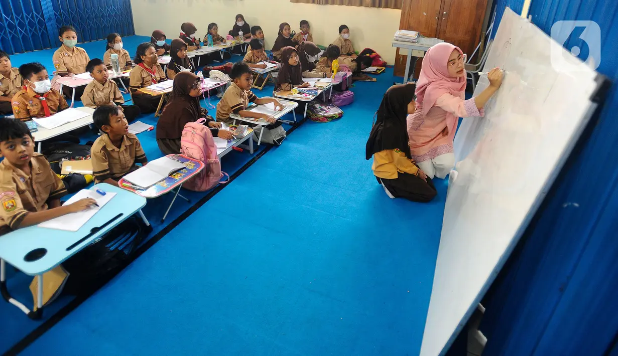 Seorang guru mengajar murid tanpa menggunakan meja dan kursi sekolah, di SDN Bojong Nangka 02, Kabupaten Bogor, Jawa Barat, Kamis (16/2/2023). Sudah lebih dari dua pekan, murid-murid di tiga ruang kelas  menerapkan kegiatan belajar mengajar beralas karpet karena belum tersedianya bangku dan meja. (merdeka.com/Arie Basuki)