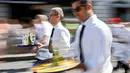 Pramusaji berlari membawa nampan dalam Waiters Race ke-21 di Fetes de Geneve, Swiss, 6 Agustus 2017. Mereka beradu kecepatan sembari menjaga keseimbangan membawa nampan berisi dua gelas dan dua botol sejauh 1,8 km. (Salvatore Di Nolfi/Keystone via AP)