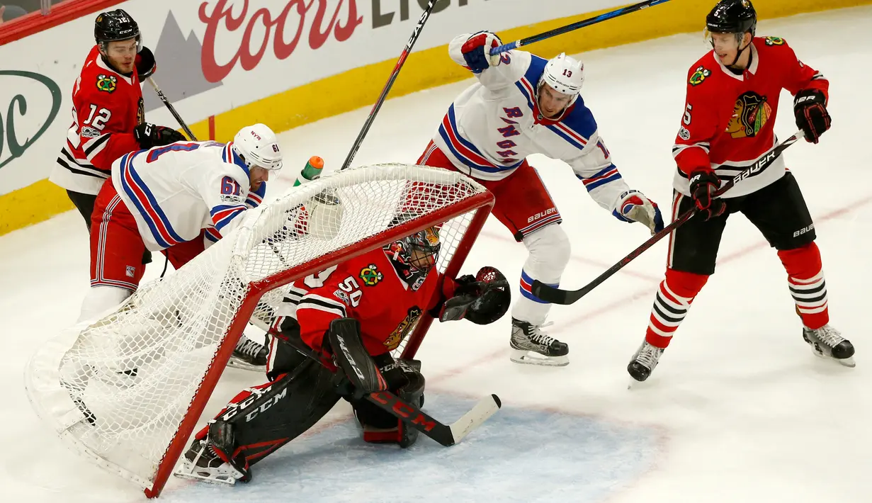 Kiper Chicago Blackhawks, Corey Crawford tertimpa gawangnya saat berebut bola dengan pemain New York Rangers saat pertandingan NHL di Chicago (15/11). Blackhawks unggul 6-3 atas Rangers. (AP/Charles Rex Arbogast)
