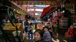 Sejumlah pengunjung berjalan di antara kios di pasar Namdaemun di Seoul (2/7/2019). Di dalam pasar ini, terdapat 58 buah bangunan yang melingkupi sekitar 9000 buah toko yang menjual berbagai jenis barang dalam harga yang murah. (AFP Photo/Minji Suh)