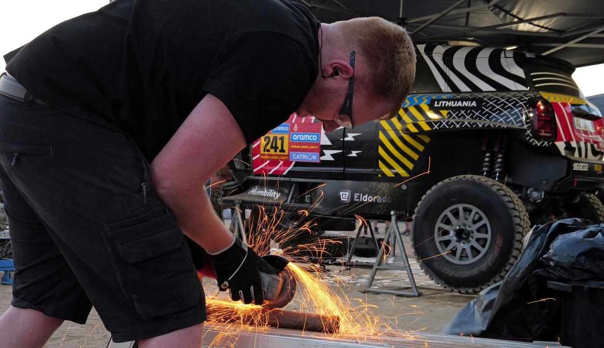 Seorang mekanik saat mempersiapkan mobil timnya menjelang Reli Dakar 2025 pada Rabu (01/01/2025) waktu setempat di Bisha, Arab Saudi. Ajang tersebut akan berlangsung pada 3 hingga 17 Januari 2025. (AFP/Valery Hache)