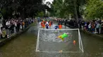Pemain sepak bola Bourton Rovers berebut bola dalam pertandingan sepak bola tradisional tahunan River Windrush di Desa Cotswolds, Bourton-on-the-Water, Inggris, Senin (28/8/2023). (AP Photo/Frank Augstein)